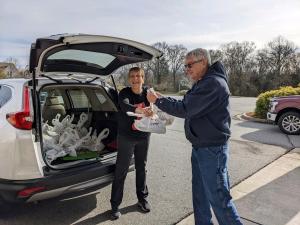 Elder Orphan Care director Kim handing meals to volunteer Jack to deliver to older friends