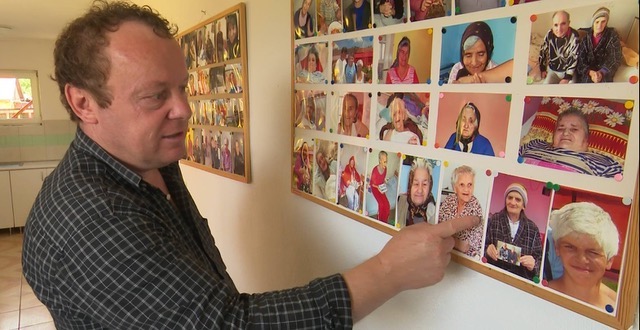 Elder Orphan Care ministry partner Viorel Pasca points to photographs of some of the older adults he has cared for