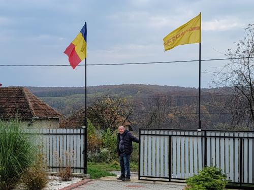 Viorel Pasca at a gate with Romanian Flag and God Will Provide flag